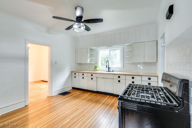 235 Elm St, Oberlin, OH 44074 - kitchen featuring stainless steel range with gas stovetop, open shelves, crown molding, light wood-style floors, and backsplash