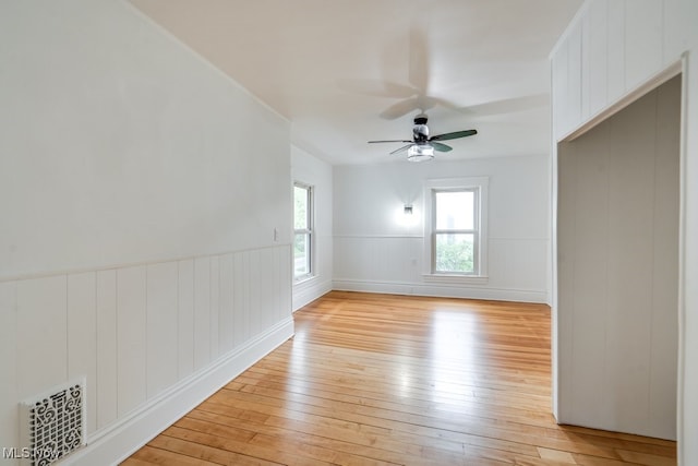 235 Elm St, Oberlin, OH 44074 - empty room with light wood finished floors, ceiling fan, a wainscoted wall, and a decorative wall