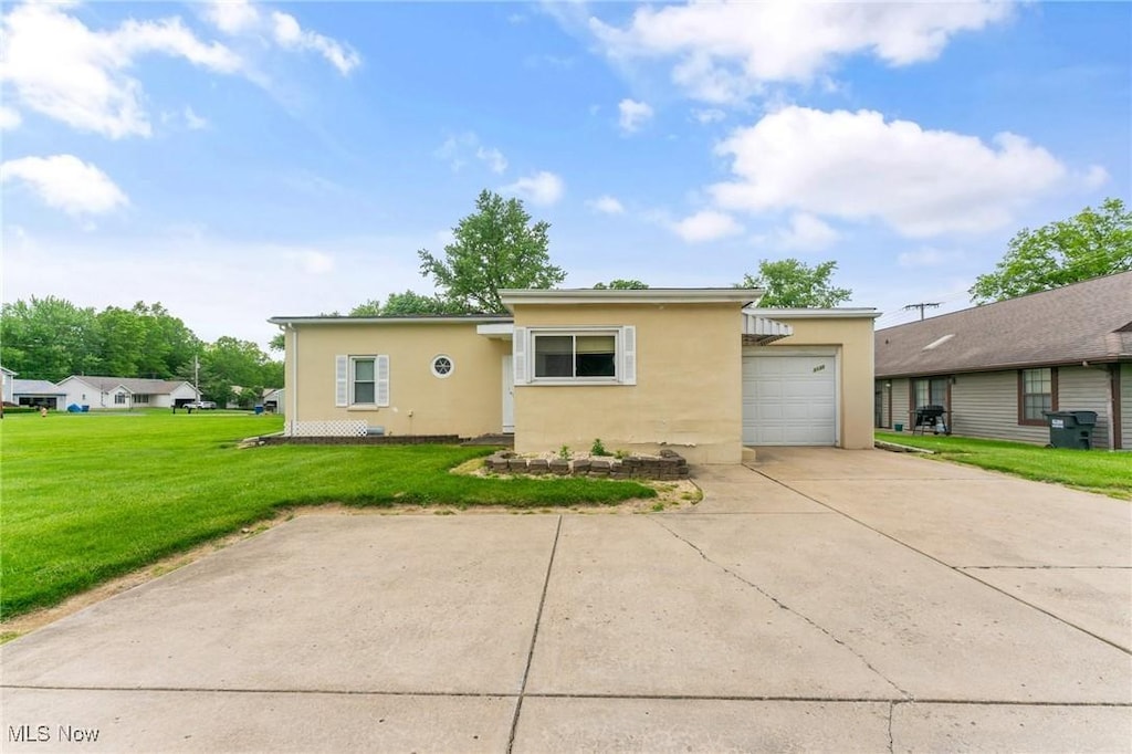3130 S Meridian Rd, Youngstown, OH 44511 - view of front of house with stucco siding, a garage, driveway, and a front yard