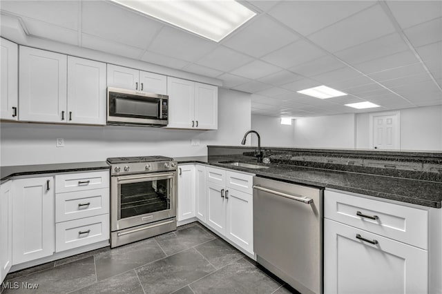 2344 Country Brook Dr, Hinckley, OH 44233 - kitchen featuring appliances with stainless steel finishes, a sink, white cabinetry, dark stone countertops, and a paneled ceiling