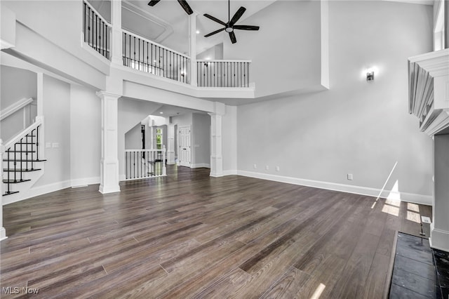 2344 Country Brook Dr, Hinckley, OH 44233 - unfurnished living room featuring ceiling fan, wood finished floors, a high ceiling, stairs, and ornate columns
