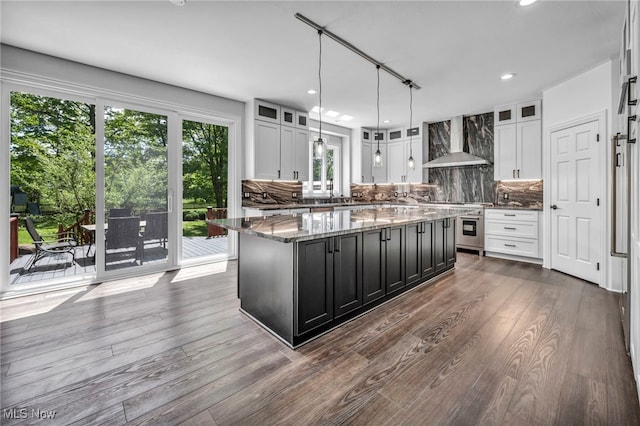 2344 Country Brook Dr, Hinckley, OH 44233 - kitchen featuring wall chimney range hood, stove, dark cabinetry, a kitchen island, and tasteful backsplash