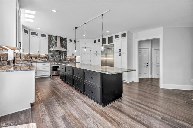 2344 Country Brook Dr, Hinckley, OH 44233 - kitchen featuring high end appliances, wall chimney exhaust hood, white cabinetry, a kitchen island, and decorative backsplash