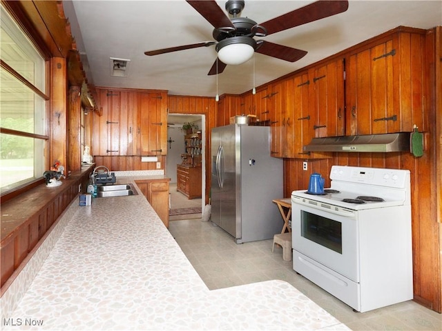 12209 Tinkers Creek Rd, Valley View, OH 44125 - kitchen featuring white electric range, under cabinet range hood, stainless steel fridge, a sink, and brown cabinets