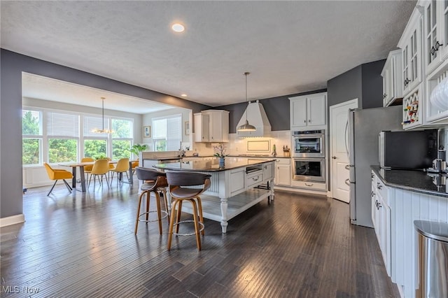 443 S Hametown Rd, Copley, OH 44321 - kitchen featuring stainless steel double oven, dark countertops, wall chimney range hood, dark wood-style floors, and glass insert cabinets