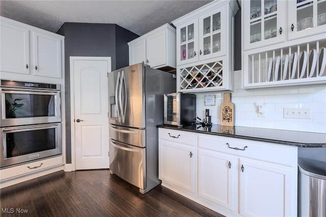 443 S Hametown Rd, Copley, OH 44321 - kitchen with appliances with stainless steel finishes, dark wood-type flooring, decorative backsplash, dark countertops, and glass insert cabinets