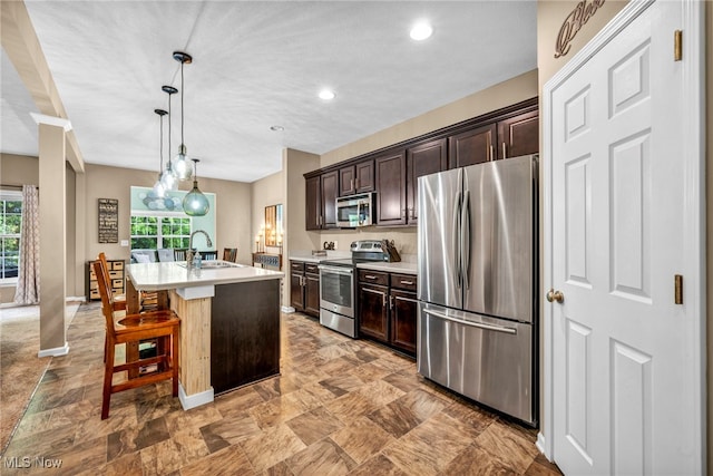 713 Westpointe Dr, Amherst, OH 44001 - kitchen with appliances with stainless steel finishes, a sink, light countertops, dark brown cabinets, and an island with sink