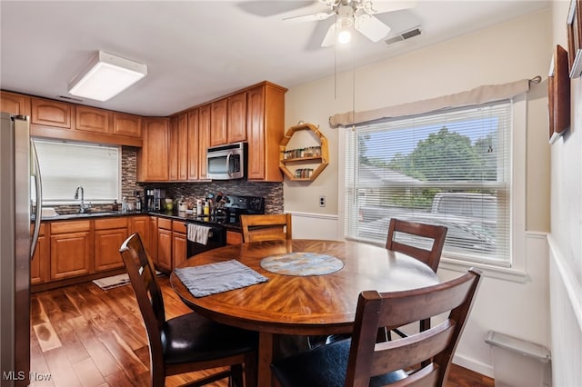153 N Doan Ave, Painesville, OH 44077 - dining space with dark wood-style flooring, a ceiling fan, and a wainscoted wall