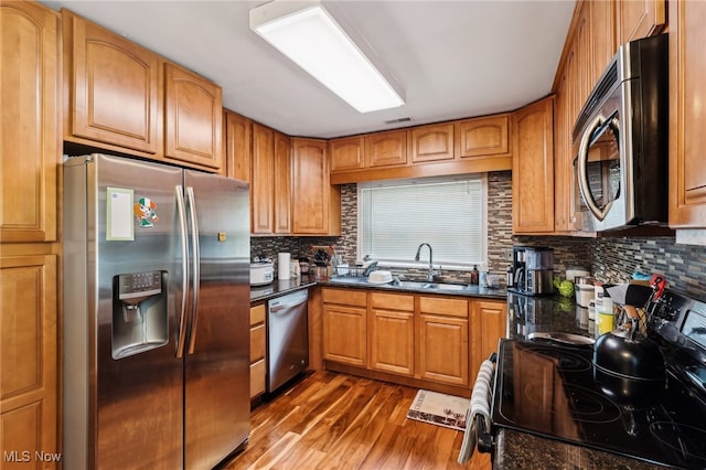 153 N Doan Ave, Painesville, OH 44077 - kitchen featuring appliances with stainless steel finishes, a sink, dark wood-style flooring, backsplash, and brown cabinetry