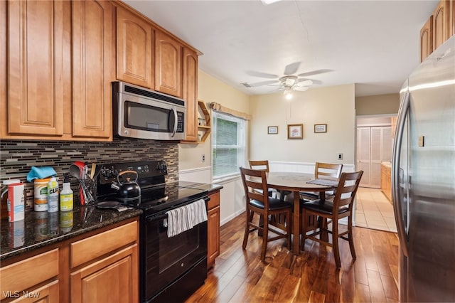 153 N Doan Ave, Painesville, OH 44077 - kitchen with stainless steel appliances, a ceiling fan, wood finished floors, tasteful backsplash, and a wainscoted wall