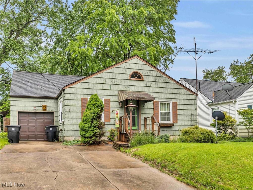 1414 Hollywood St NE, Warren, OH 44483 - view of front of house featuring concrete driveway, a garage, a front yard, and a shingled roof