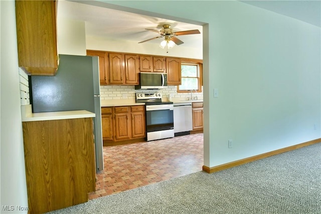 5990 Stewart Sharon Rd, Hubbard, OH 44425 - kitchen featuring appliances with stainless steel finishes, decorative backsplash, ceiling fan, brown cabinetry, and light countertops