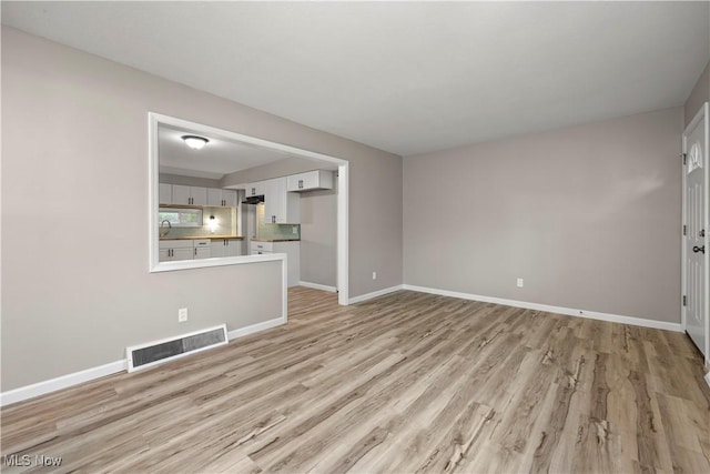 6265 Jaycox Rd, North Ridgeville, OH 44039 - unfurnished living room with light wood-style floors, baseboards, and a sink