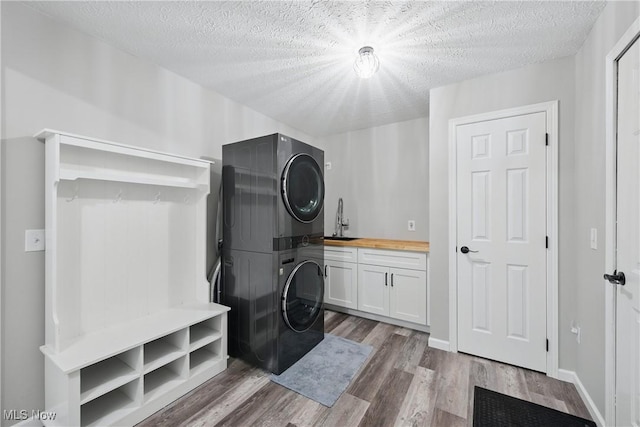 301 Tower Ln, Amherst, OH 44001 - laundry area with stacked washer / dryer, cabinet space, wood finished floors, and a textured ceiling