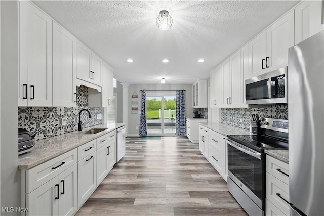 301 Tower Ln, Amherst, OH 44001 - kitchen with appliances with stainless steel finishes, a sink, decorative columns, white cabinetry, and recessed lighting
