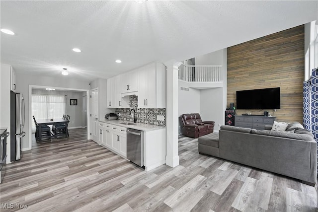301 Tower Ln, Amherst, OH 44001 - kitchen featuring appliances with stainless steel finishes, light countertops, a sink, light wood-type flooring, and white cabinetry