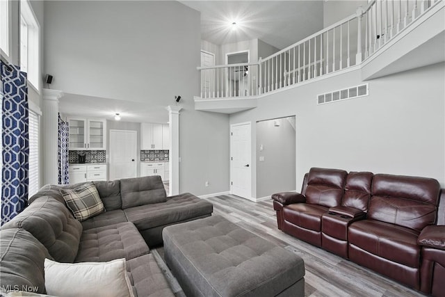 301 Tower Ln, Amherst, OH 44001 - living room with ornate columns, a towering ceiling, light wood-style floors, baseboards, and plenty of natural light