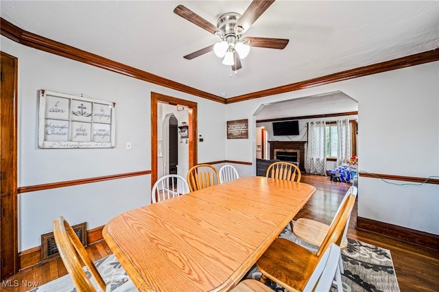 3906 Redfern Rd, Parma, OH 44134 - dining area featuring arched walkways, a ceiling fan, hardwood / wood-style floors, a fireplace, and crown molding