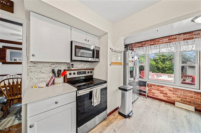 3906 Redfern Rd, Parma, OH 44134 - kitchen with stainless steel appliances, white cabinets, backsplash, light wood-style flooring, and light countertops