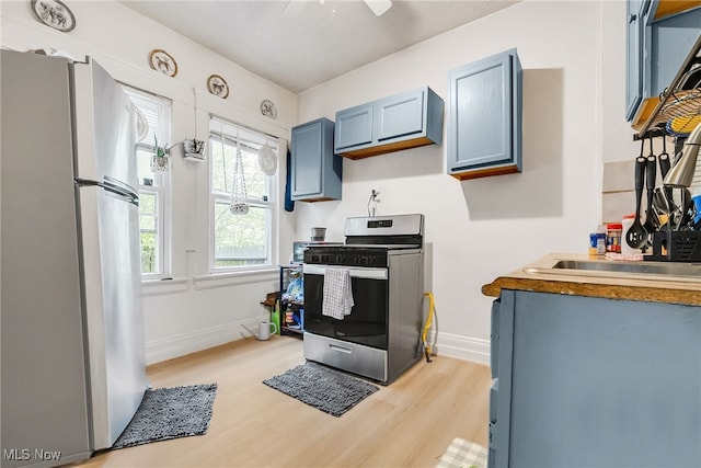 11020 Woodstock Ave, Cleveland, OH 44104 - kitchen with stainless steel appliances, light wood-style flooring, baseboards, and blue cabinets