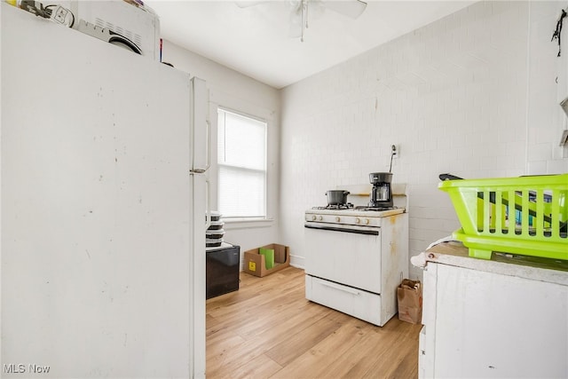 11020 Woodstock Ave, Cleveland, OH 44104 - kitchen with white appliances, light wood-type flooring, a ceiling fan, tile walls, and light countertops