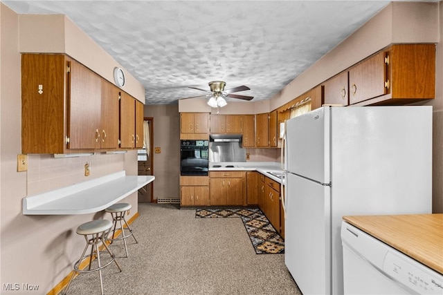 68951 Pine Terrace Rd, Bridgeport, OH 43912 - kitchen with white appliances, under cabinet range hood, brown cabinets, a ceiling fan, and tasteful backsplash