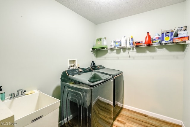 2042 Summer Evening Dr, Canal Fulton, OH 44614 - laundry room with washing machine and clothes dryer, light wood-style flooring, baseboards, and a textured ceiling