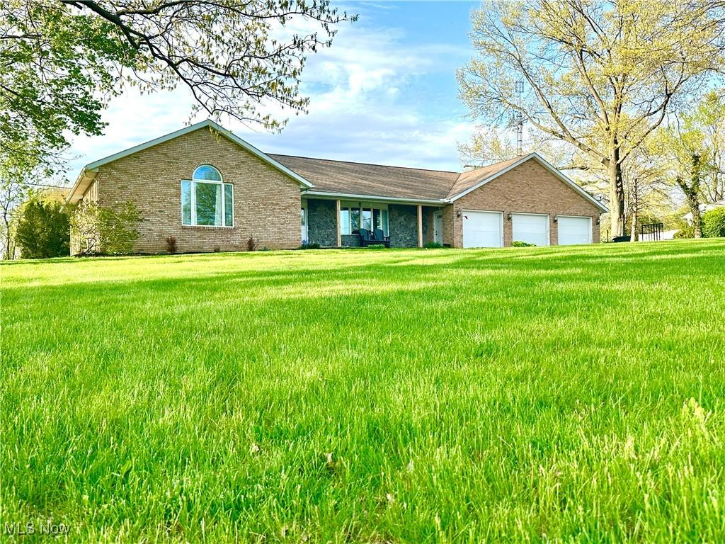 13946 Highview Dr, Dalton, OH 44618 - ranch-style home with brick siding, a garage, and a front lawn