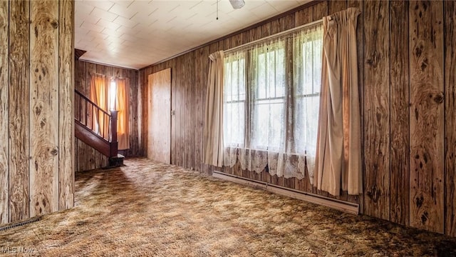 8045 Old Town Rd, East Fultonham, OH 43777 - carpeted empty room featuring wooden walls, stairs, and a baseboard heating unit