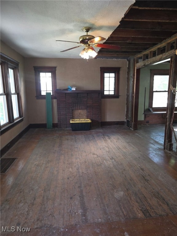 1119 W 11th St, Lorain, OH 44052 - unfurnished living room with a brick fireplace, wood-type flooring, a ceiling fan, baseboards, and a textured ceiling
