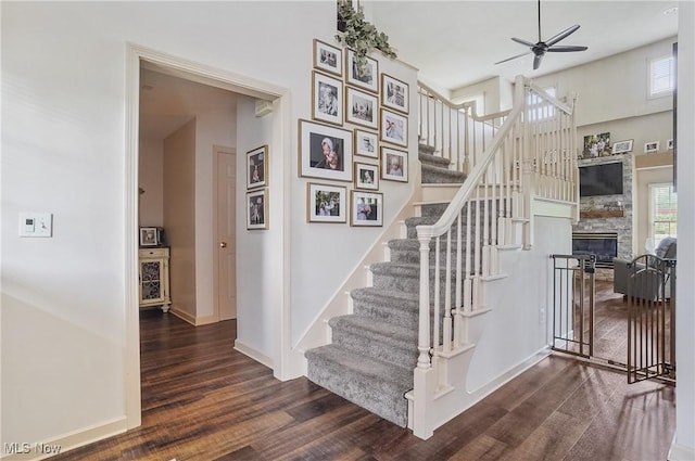 8550 Ivy Hill Dr Unit 16, Poland, OH 44514 - staircase with wood finished floors, ceiling fan, a stone fireplace, baseboards, and a towering ceiling