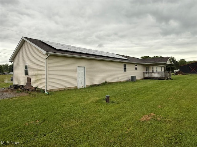 6920 Riverside Rd SE, Gnadenhutten, OH 44629 - back of property with solar panels, a lawn, a wooden deck, and central air condition unit