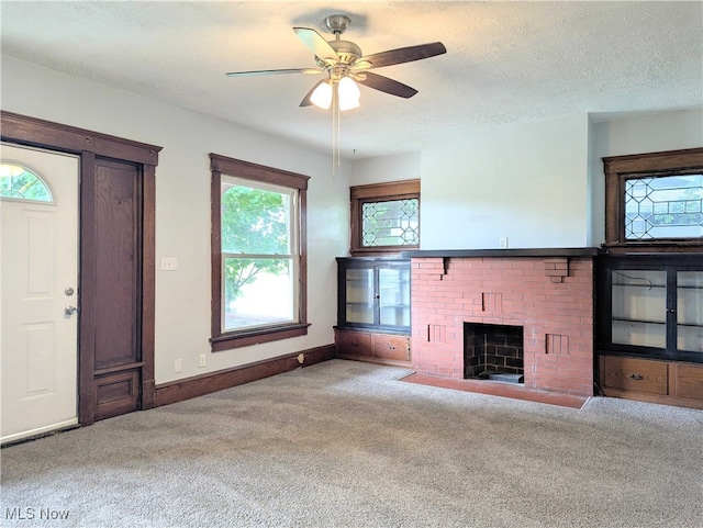 925 Camden Ave SW, Canton, OH 44706 - unfurnished living room featuring carpet flooring, a fireplace, ceiling fan, baseboards, and a textured ceiling