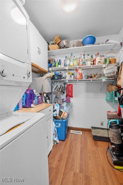 4948 State Route 61, Mount Gilead, OH 43338 - laundry area with stacked washer and clothes dryer, cabinet space, and light wood finished floors