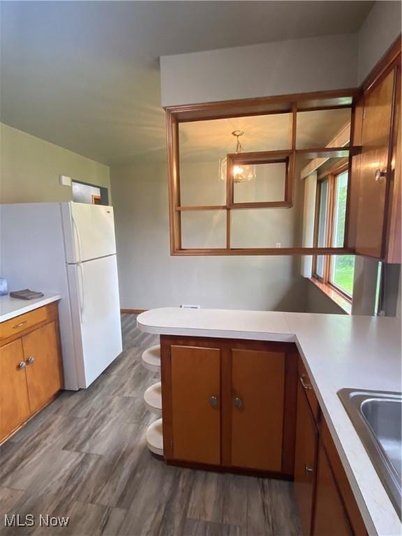 1414 W 40th St, Lorain, OH 44053 - kitchen with light countertops, brown cabinetry, dark wood-type flooring, freestanding refrigerator, and a sink