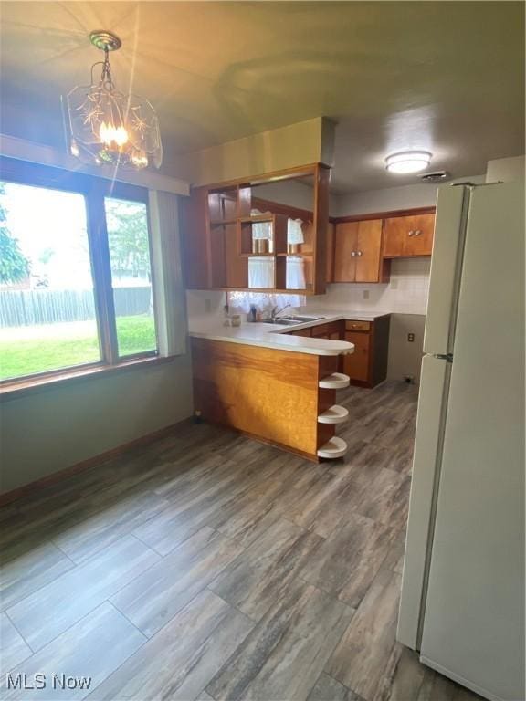 1414 W 40th St, Lorain, OH 44053 - kitchen featuring freestanding refrigerator, a peninsula, brown cabinetry, open shelves, and light countertops