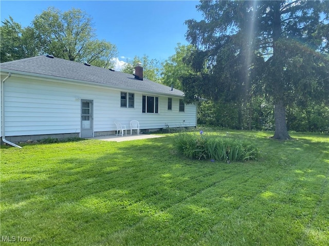 1414 W 40th St, Lorain, OH 44053 - rear view of house with a chimney, a lawn, a patio area, and a shingled roof