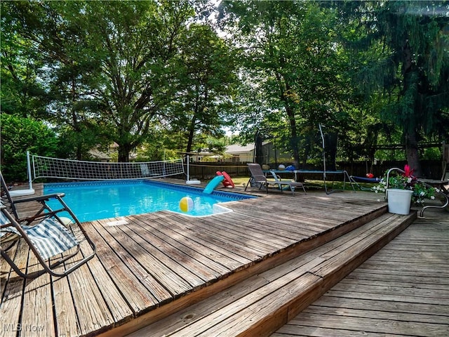 6221 Brighton Dr, North Olmsted, OH 44070 - view of swimming pool with a trampoline, a fenced backyard, and a wooden deck