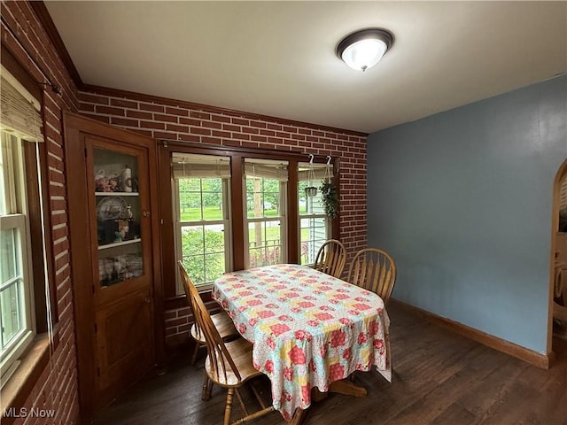 7350 Center Rd, Saybrook, OH 44004 - dining space featuring baseboards, dark wood-style floors, and brick wall