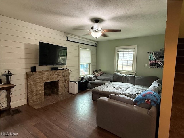 7350 Center Rd, Saybrook, OH 44004 - living room with dark wood-type flooring, a ceiling fan, a textured ceiling, a fireplace, and wooden walls