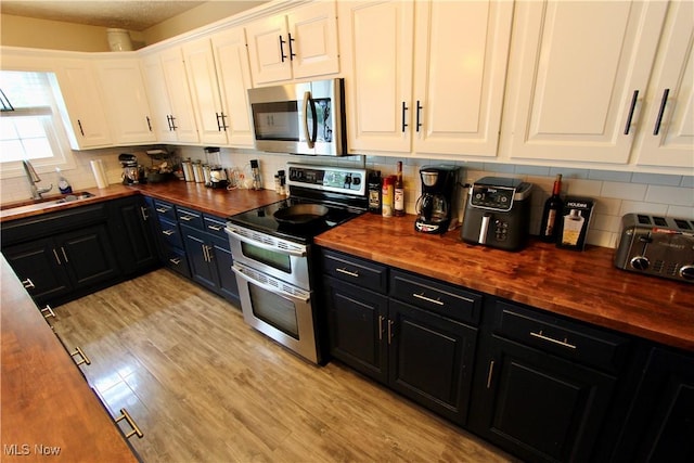 615 Wolf Ave, Wadsworth, OH 44281 - kitchen featuring butcher block counters, stainless steel appliances, a sink, and dark cabinets