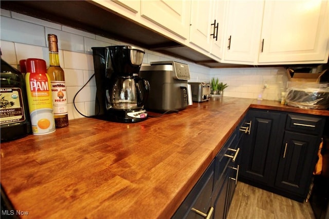 615 Wolf Ave, Wadsworth, OH 44281 - kitchen featuring butcher block countertops, tasteful backsplash, white cabinetry, and wood finished floors