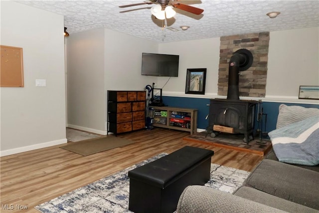5430 Barkwood Dr, Sheffield Village, OH 44054 - living area with a wood stove, ceiling fan, wood finished floors, baseboards, and a textured ceiling