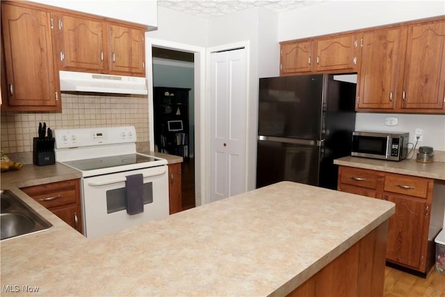 5430 Barkwood Dr, Sheffield Village, OH 44054 - kitchen featuring under cabinet range hood, freestanding refrigerator, white range with electric cooktop, stainless steel microwave, and brown cabinetry