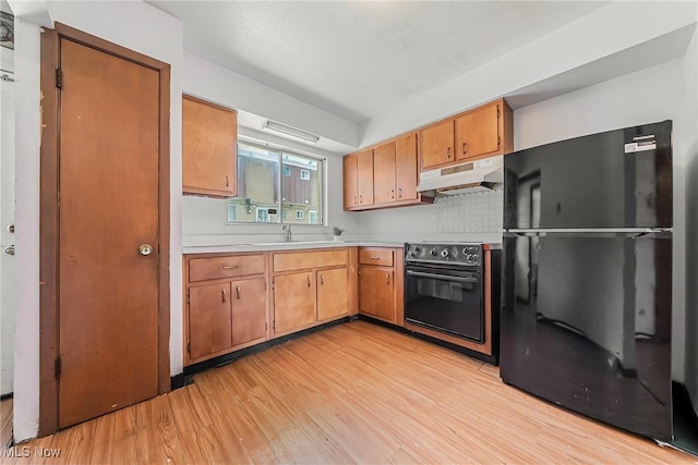 27701 Mills Ave Unit 2N, Euclid, OH 44132 - kitchen with freestanding refrigerator, under cabinet range hood, range with electric stovetop, light wood-style floors, and light countertops