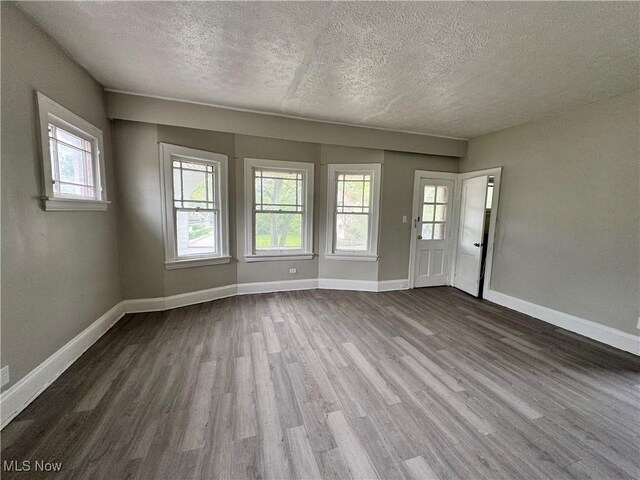 3293 E 121st St, Cleveland, OH 44120 - unfurnished living room with a textured ceiling, dark wood finished floors, healthy amount of natural light, and baseboards