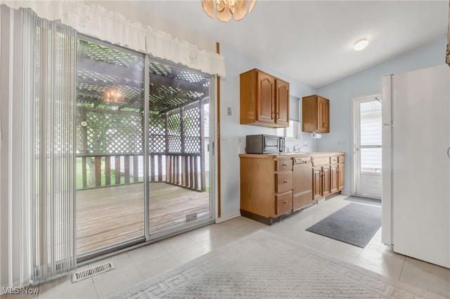 36948 S Lake Shore Blvd, Eastlake, OH 44095 - kitchen with freestanding refrigerator, dishwasher, light tile patterned floors, lofted ceiling, and brown cabinetry