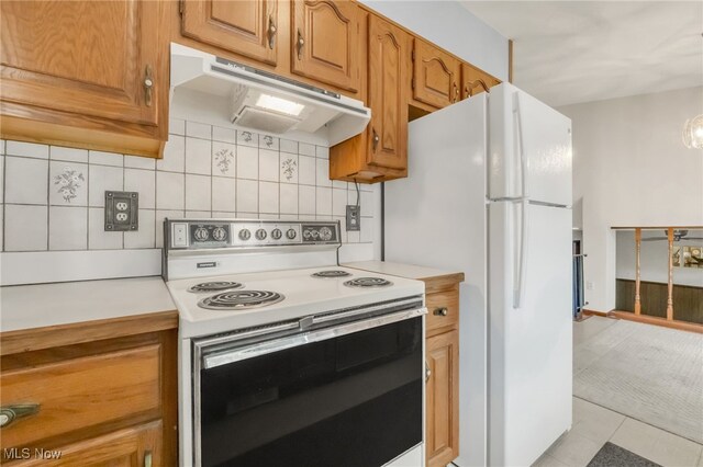 36948 S Lake Shore Blvd, Eastlake, OH 44095 - kitchen featuring white appliances, under cabinet range hood, tasteful backsplash, light countertops, and brown cabinetry