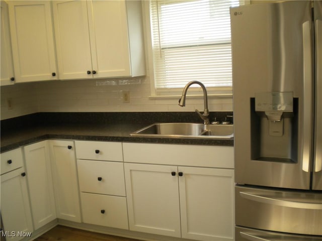 161 25th St NW, Barberton, OH 44203 - kitchen featuring stainless steel fridge with ice dispenser, a sink, white cabinets, and backsplash