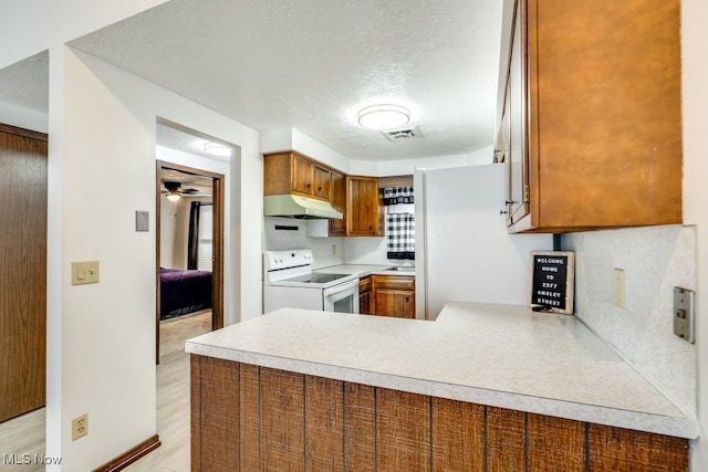 2377 Ansley St, Alliance, OH 44601 - kitchen with white appliances, under cabinet range hood, a peninsula, light countertops, and a textured ceiling